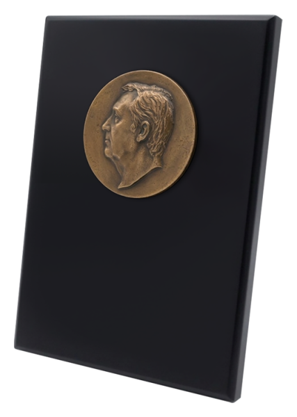 Metopa personalizada con cara en bronceReferencia: PL0446Rostro en bronce sobre una metopa de madera maciza lacada en negro.El rostro se hace totalmente personalizado y es tallado a partir de una fotografía consiguiendo un resultado sorprendente y fiel.Medida: 210x280mm.